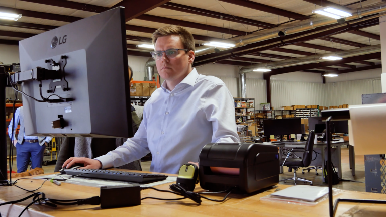 A warehouse manager uses a desktop computer with FBA purchase order software to calculate how much to restock for FBA.